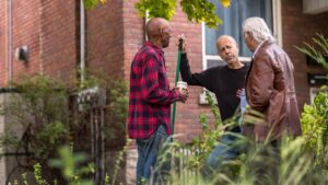 Three neighbors talking in a yard
