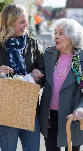 Two women with interlinked arms walking down the street